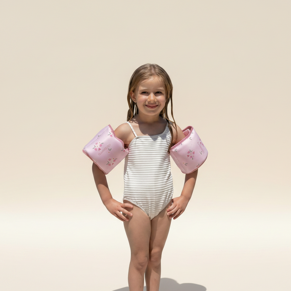 Young girl with pink arm floats standing by a pool