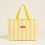 Yellow striped tote bag with a red label on a light gray background
