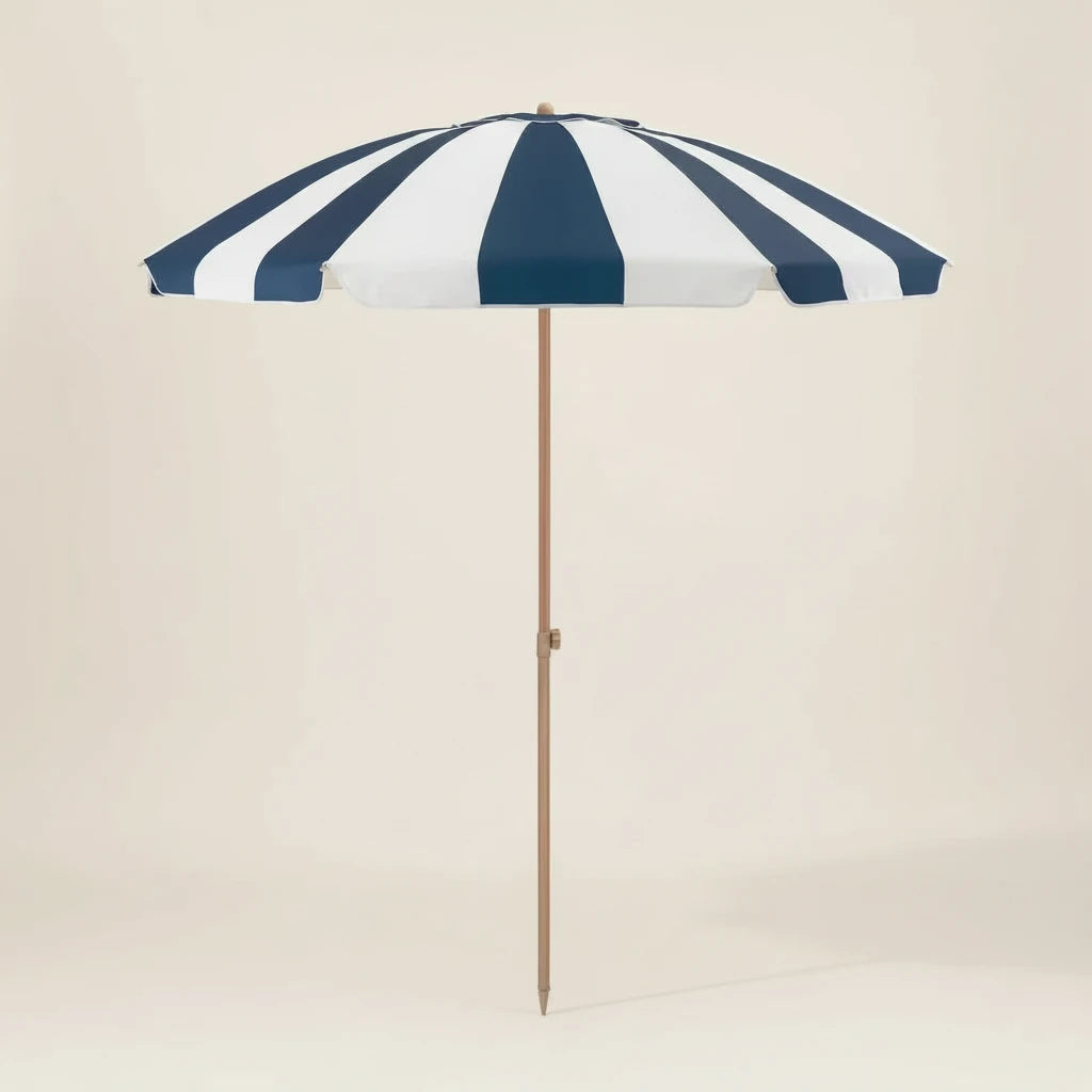Navy and white striped beach umbrella with a wooden pole on a beige background