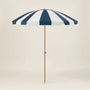 Navy and white striped beach umbrella with a wooden pole on a beige background