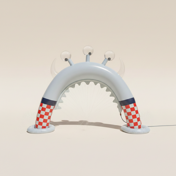 Inflatable arch with checkered pattern on a grassy area with trees and building in the background